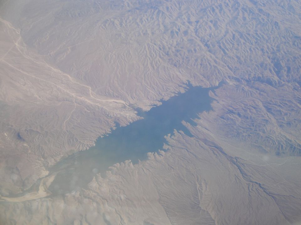 Aerial view of a large body of water surrounded by dry, mountainous terrain