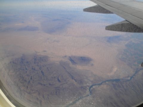 1989 Ford Taurus - View from an airplane window shows a desert landscape with a winding river and a distant wing.