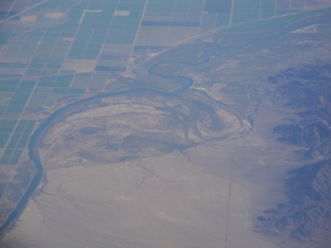 1989 Ford Taurus - An aerial perspective captures a meandering river flowing through cultivated fields and arid terrain.