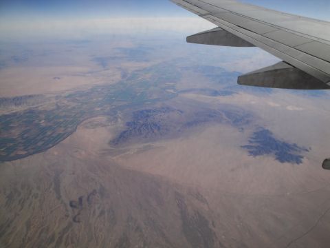 1989 Ford Taurus - View from an airplane window shows a vast desert landscape with agricultural fields along a river.