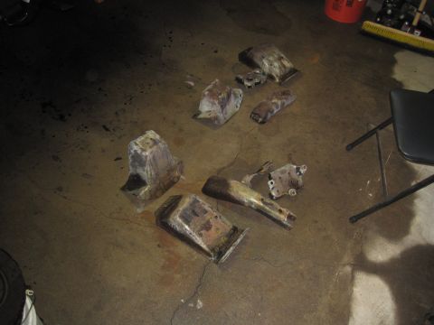 1979 Ford Bronco - Various rusty vehicle suspension parts are laid out on a concrete floor.