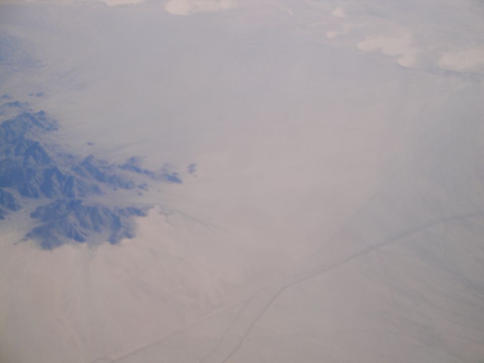 Aerial view of a desert landscape with mountains on the left and a road stretching into the distance