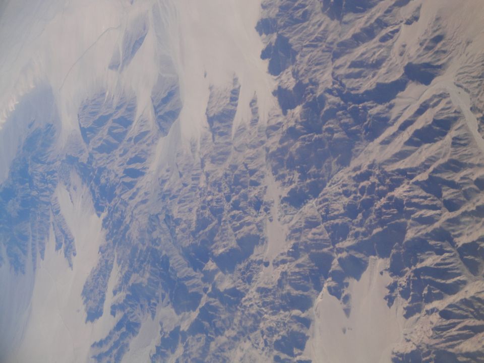 Aerial view of arid desert mountains and valleys under a hazy sky