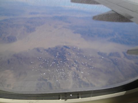 1989 Ford Taurus - View from an airplane window shows a vast, arid landscape below with a scattering of white debris.