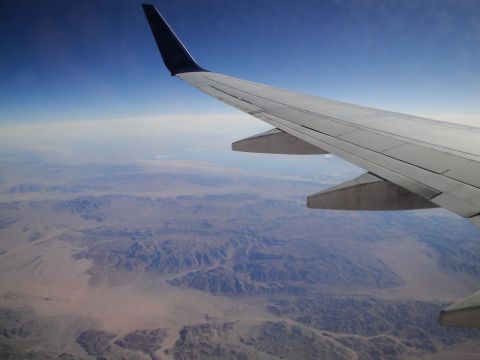 1989 Ford Taurus - View from an airplane window shows a wing and the arid landscape below.