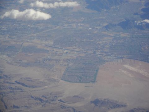 1989 Ford Taurus - An aerial perspective captures a city within a vast desert landscape, with mountains in the distance.