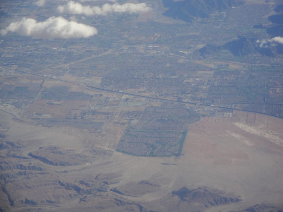 Aerial view of a city with a highway running through it, bordered by desert terrain and mountains