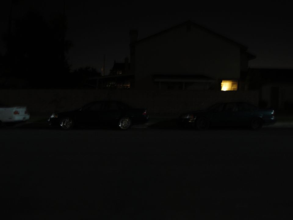 Two sedans parked on street at night