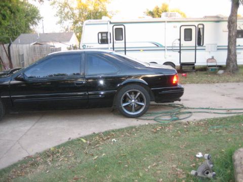 1996 Ford Thunderbird - A black coupe is parked on a driveway with an RV in the background.