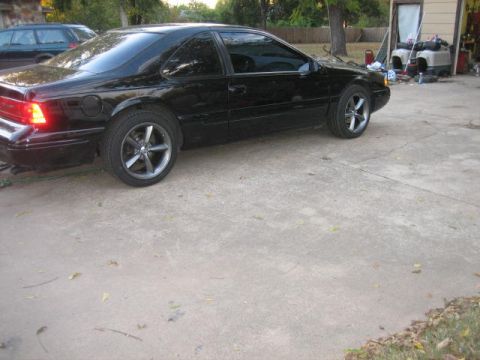 1996 Ford Thunderbird - A black 1996 Ford Thunderbird coupe is parked in a driveway next to a garage.