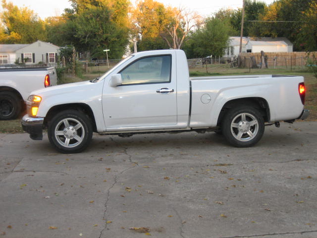 Side view of a white pickup truck with a chrome grille and five-spoke wheels