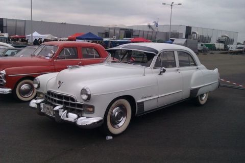 1991 Ford LTD Crown Victoria - A classic white Cadillac sedan is parked next to a red car at an outdoor event.