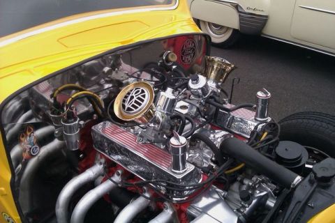 1991 Ford LTD Crown Victoria - A highly customized V8 engine with chrome and gold accents is visible in the engine bay of a yellow car, with another classic car in the ba…