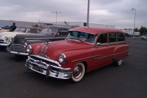 1991 Ford LTD Crown Victoria - A vintage red station wagon with wood paneling is parked alongside other classic cars.