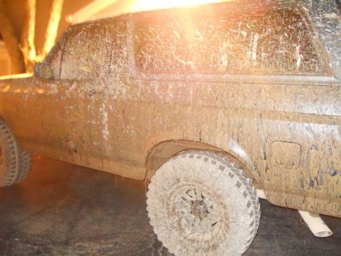 1996 Ford Bronco - This heavily mud-splattered SUV, likely from the early 1990s, is viewed from its side.
