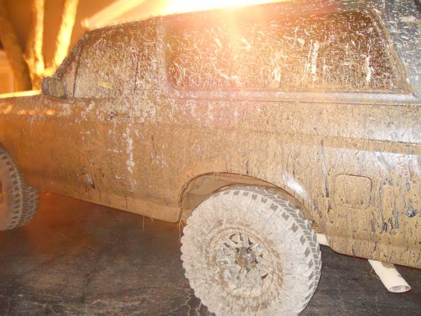 Mud-covered SUV side view, showing tires and body panels caked in dirt