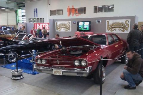 1991 Ford LTD Crown Victoria - A red sedan with its hood open is displayed next to a black convertible at a car show.