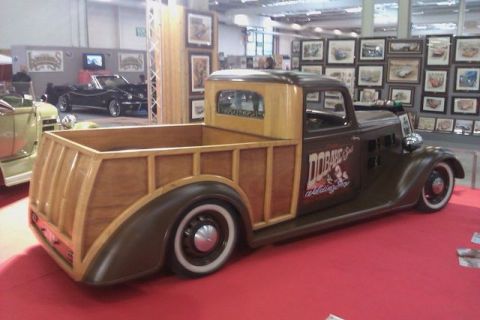 1991 Ford LTD Crown Victoria - A custom woodie pickup truck is displayed indoors with artwork on the walls and other vehicles nearby.