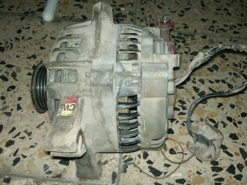 1998 Ford Crown Victoria - Close-up of a dusty alternator, possibly from a vehicle, with a partial label visible.