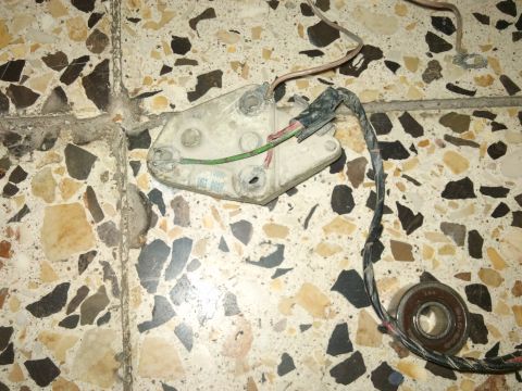 1998 Ford Crown Victoria - A car part, possibly an alternator component, with wiring and a bearing, lies on a terrazzo floor.