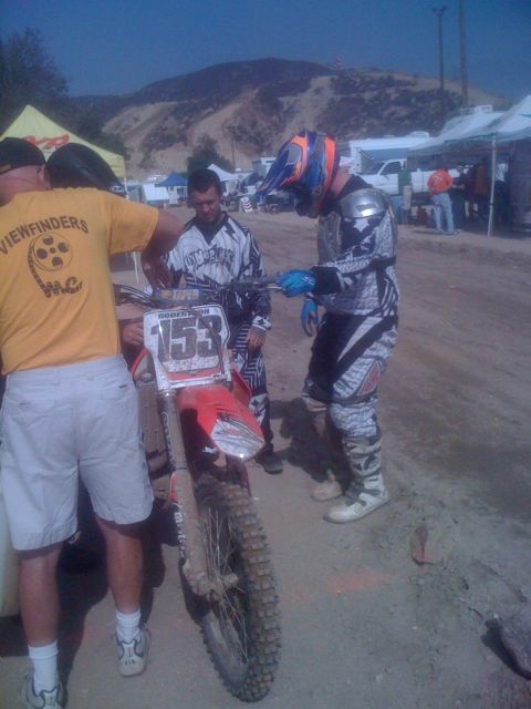 1968 Ford Mustang - A motocross motorcycle with the number 153 is being attended to by riders and support crew at an outdoor event.