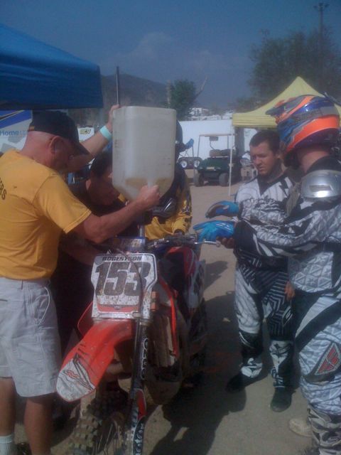 1968 Ford Mustang - A rider's bike is being refueled by a person in a yellow shirt while other riders wait.