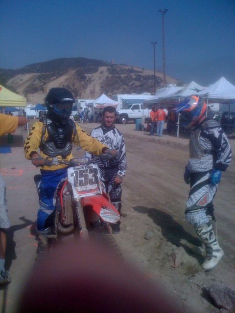 1968 Ford Mustang - A motocross rider prepares for an event, with other participants and tents visible in the background.