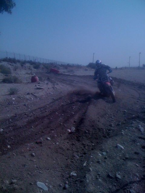 1968 Ford Mustang - A lone motocross rider navigates a turn on a dirt track under a hazy sky.