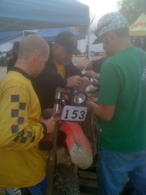 1968 Ford Mustang - A group of people are gathered around a dirt bike, appearing to perform maintenance or repairs.