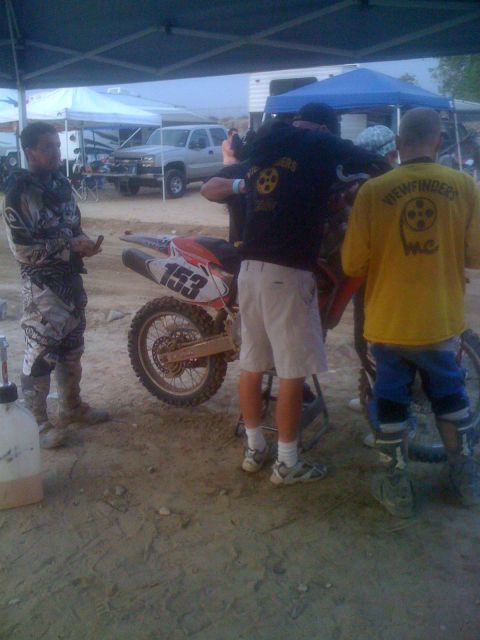 1968 Ford Mustang - A dirt bike with the number 153 is attended to by people in racing gear under a canopy.