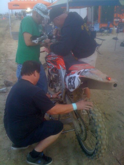 1968 Ford Mustang - Mechanics work on a dirt bike at an outdoor event, with the number 153 visible on its side.