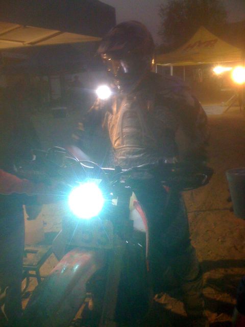 1968 Ford Mustang - A person in riding gear illuminates the area with a flashlight while standing next to a motorcycle at night.