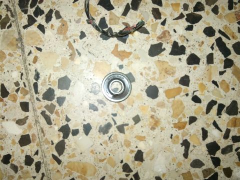 1998 Ford Crown Victoria - A close-up of a bearing and some electrical wires resting on a speckled terrazzo floor.