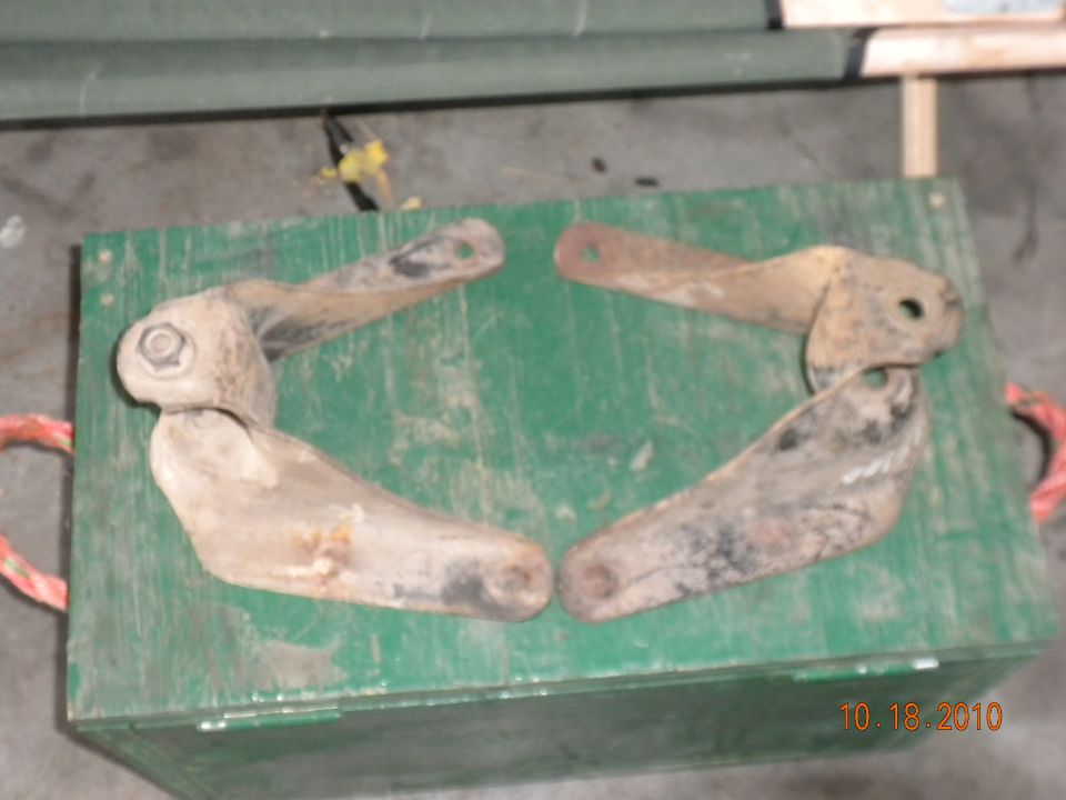 Four rusty metal vehicle parts on a green box