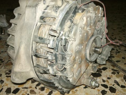 1998 Ford Crown Victoria - A dusty automotive alternator is shown in a close-up view, revealing its internal components and wiring.