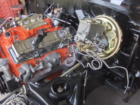 1970 Chevrolet Camaro - Close-up of a V8 engine with orange block and chrome valve covers, likely undergoing restoration or upgrade.
