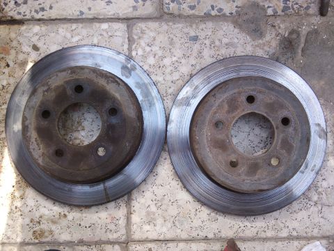 1998 Ford Crown Victoria - Two used brake rotors are shown on a tiled surface, indicating a part replacement.