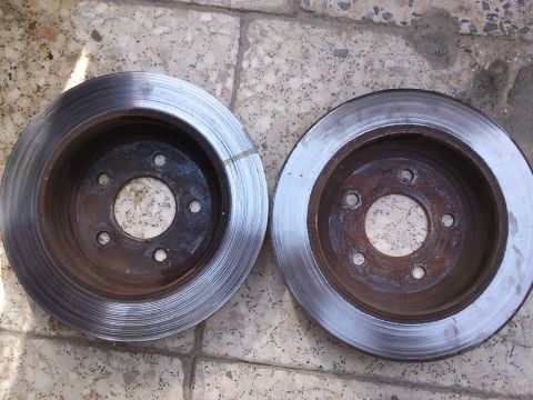 1998 Ford Crown Victoria - Two brake rotors are shown resting on a tiled surface, likely awaiting installation or replacement.