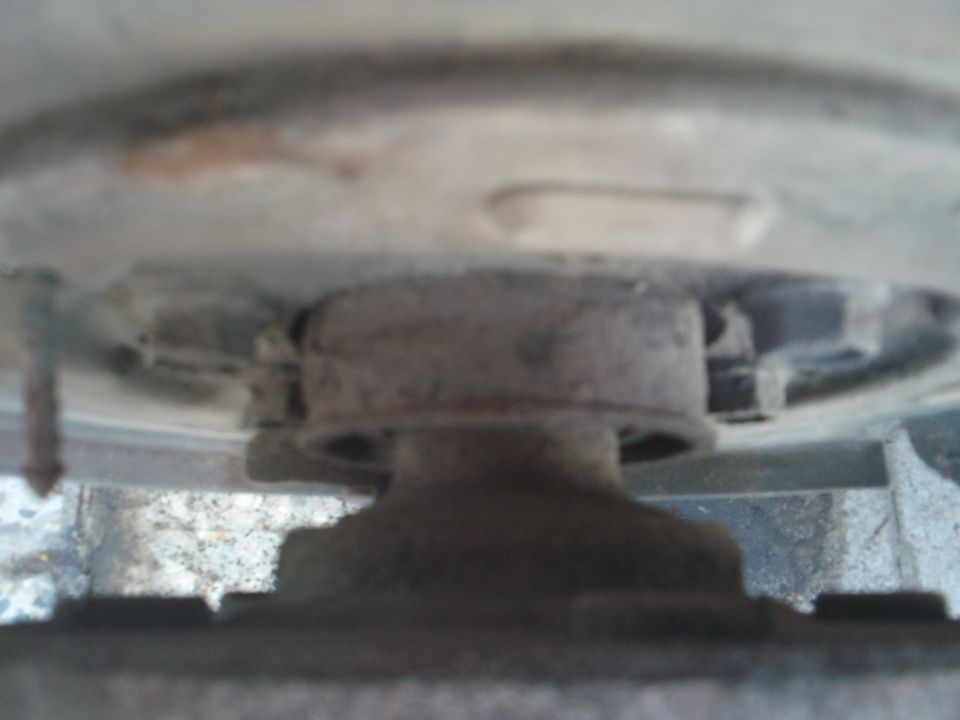 Close-up of a vehicle's brake caliper mount, showing rusty metal components
