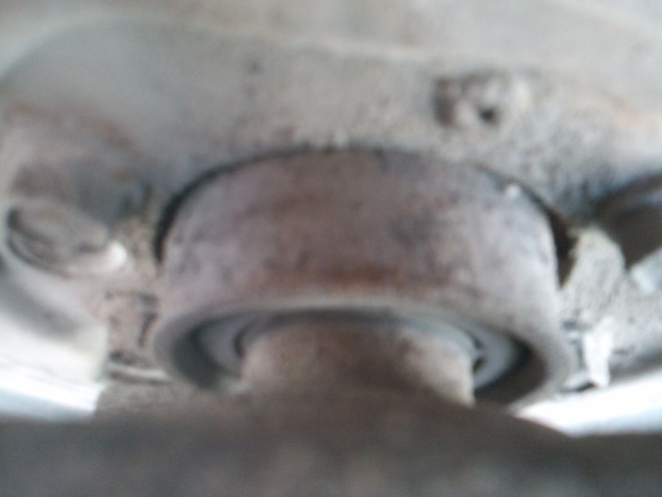 Close-up of a rusty, circular vehicle suspension part with a bearing visible