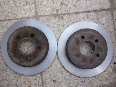 1998 Ford Crown Victoria - A new brake rotor sits next to a used one, likely for an e-brake job.