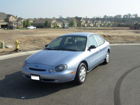 1997 Ford Taurus - Light blue 1997 Ford Taurus sedan parked on a street in a suburban neighborhood.