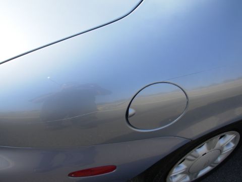 1997 Ford Taurus - Close-up of a silver car's fuel door and rear quarter panel, showing a scratch on the paint.