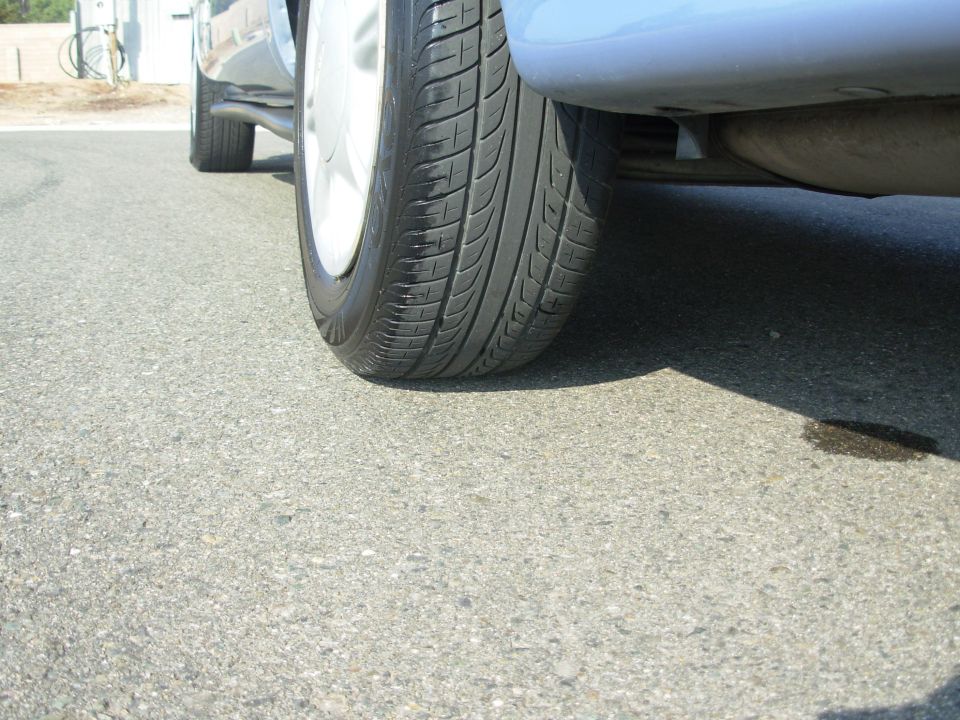 Close-up of a car's front tire and the underside of the vehicle, showing the exhaust pipe