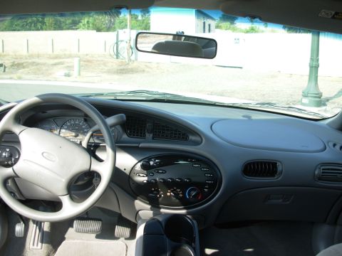 1997 Ford Taurus - The interior of a car shows a dashboard with a steering wheel and radio controls, with "SUPERMOTORS" visible on the floor mat.