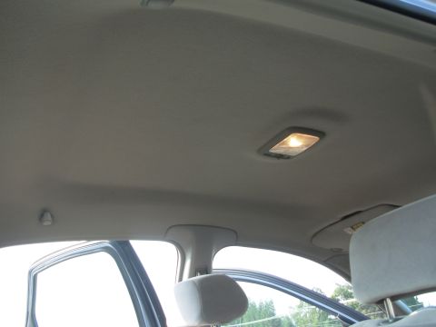 1997 Ford Taurus - The interior ceiling of a car shows a dome light and a sun visor, with a portion of the door frame and headrest visible.