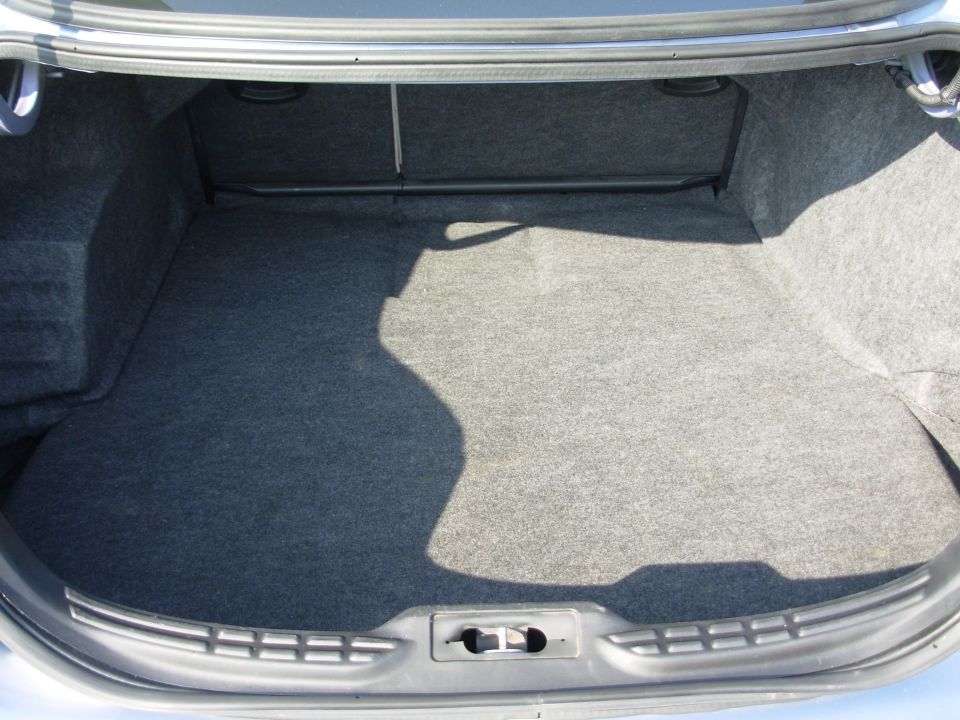 Car trunk interior with gray carpet lining and a metal bar across the top. A water mark is visible on the carpet
