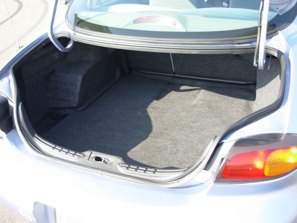 Open trunk of a silver sedan with gray carpet lining