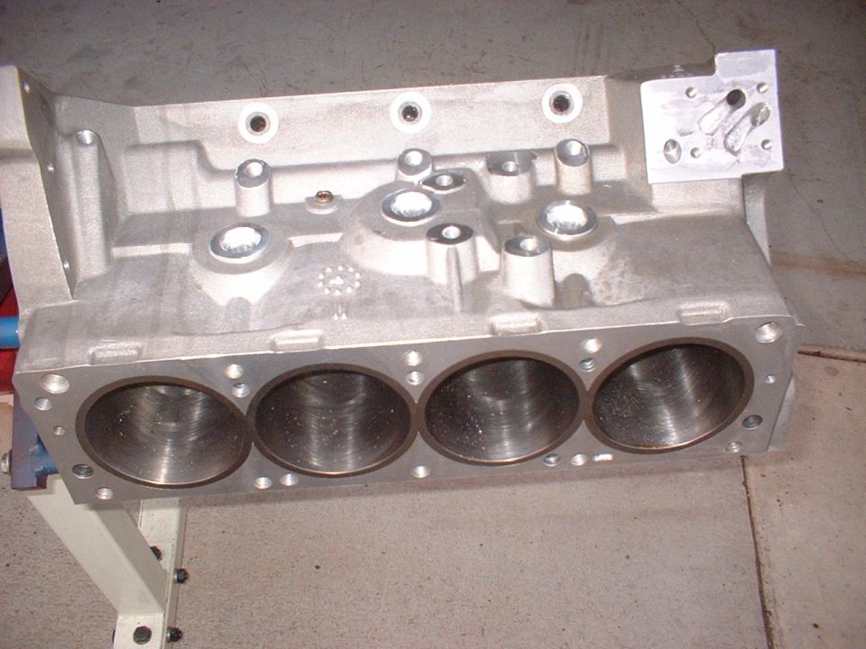 Aluminum V8 engine block with four cylinders visible, mounted on a stand
