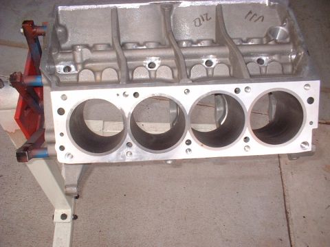 1965 Shelby Cobra - An aluminum engine block is shown on a stand, with visible cylinder bores and some markings on the top.